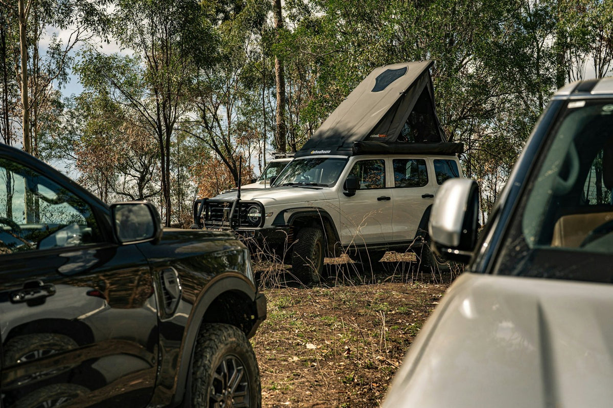 Overlanding vehicle with rooftop tent at camp